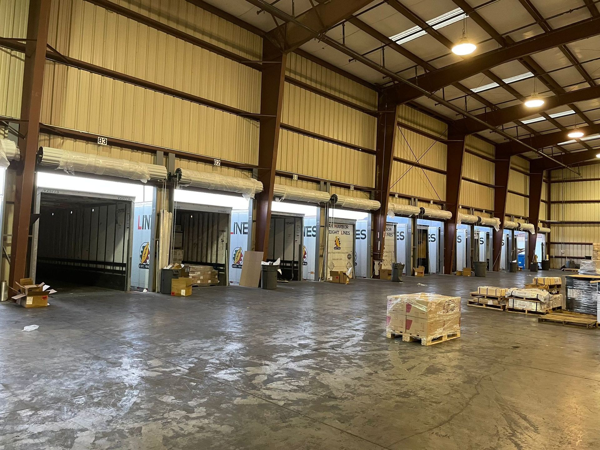 Interior view of a warehouse with multiple loading docks and various packages stacked on pallets ready for shipping.